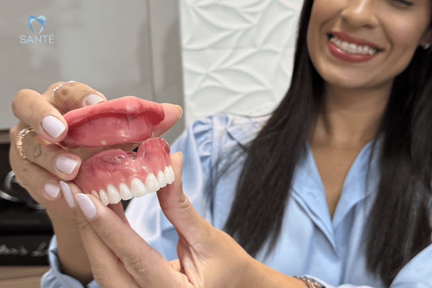 Mão segurando uma prótese protocolo superior sobre implantes, mostrando os encaixes que garantem dentes firmos.