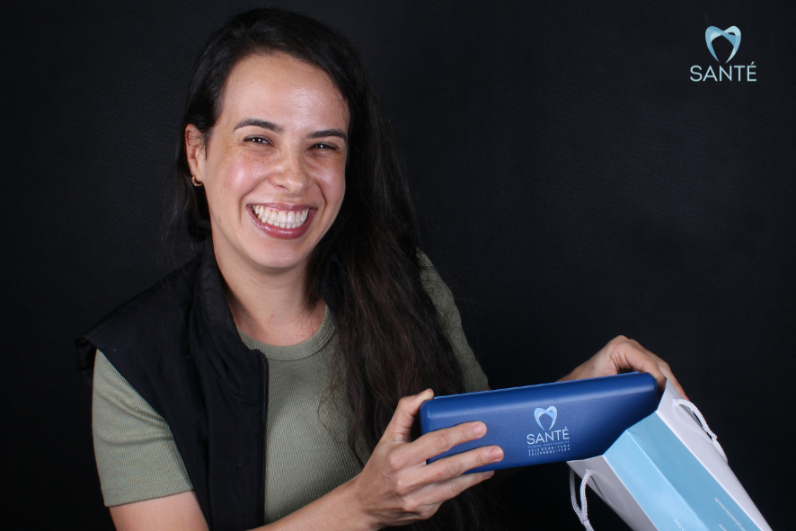 Paciente sorridente segura kit exclusivo da Santé Odontologia após finalizar sua profilaxia e limpeza dental em Belo Horizonte.